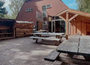 Terras van groepsaccommodatie Het Noordhuis in Drenthe, met tafels en stoelen voor groepen, ideaal voor kampgangers en families om buiten te eten en te ontspannen.